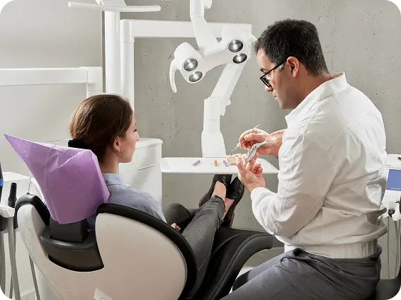 A dentist at Issa Dental explaining the root canal therapy process to a patient using a dental model to illustrate how the procedure saves a natural tooth.