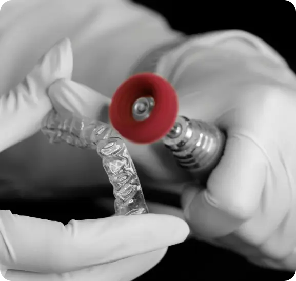 A dental professional adjusting a clear retainer with a precision polishing tool for a custom fit at Issa Dental Group.