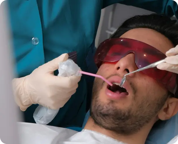 A patient wearing protective red eyewear during a laser-assisted dental treatment at Issa Dental Group.