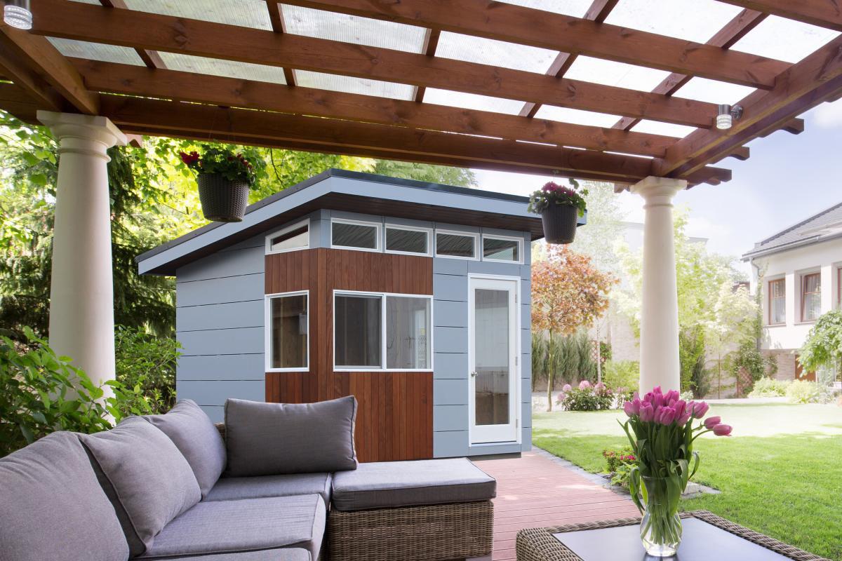 Modern backyard shed beside a covered patio with outdoor seating