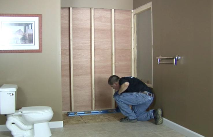 Worker preparing a bathroom wall for shower installation