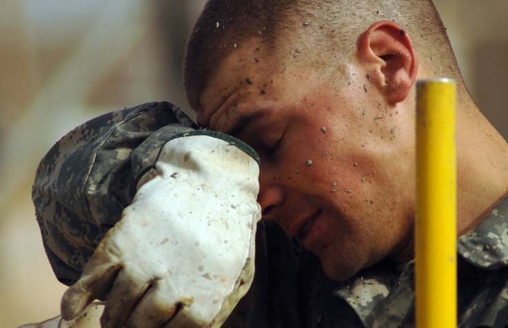 Worker wiping sweat from his face while working outdoors in the heat