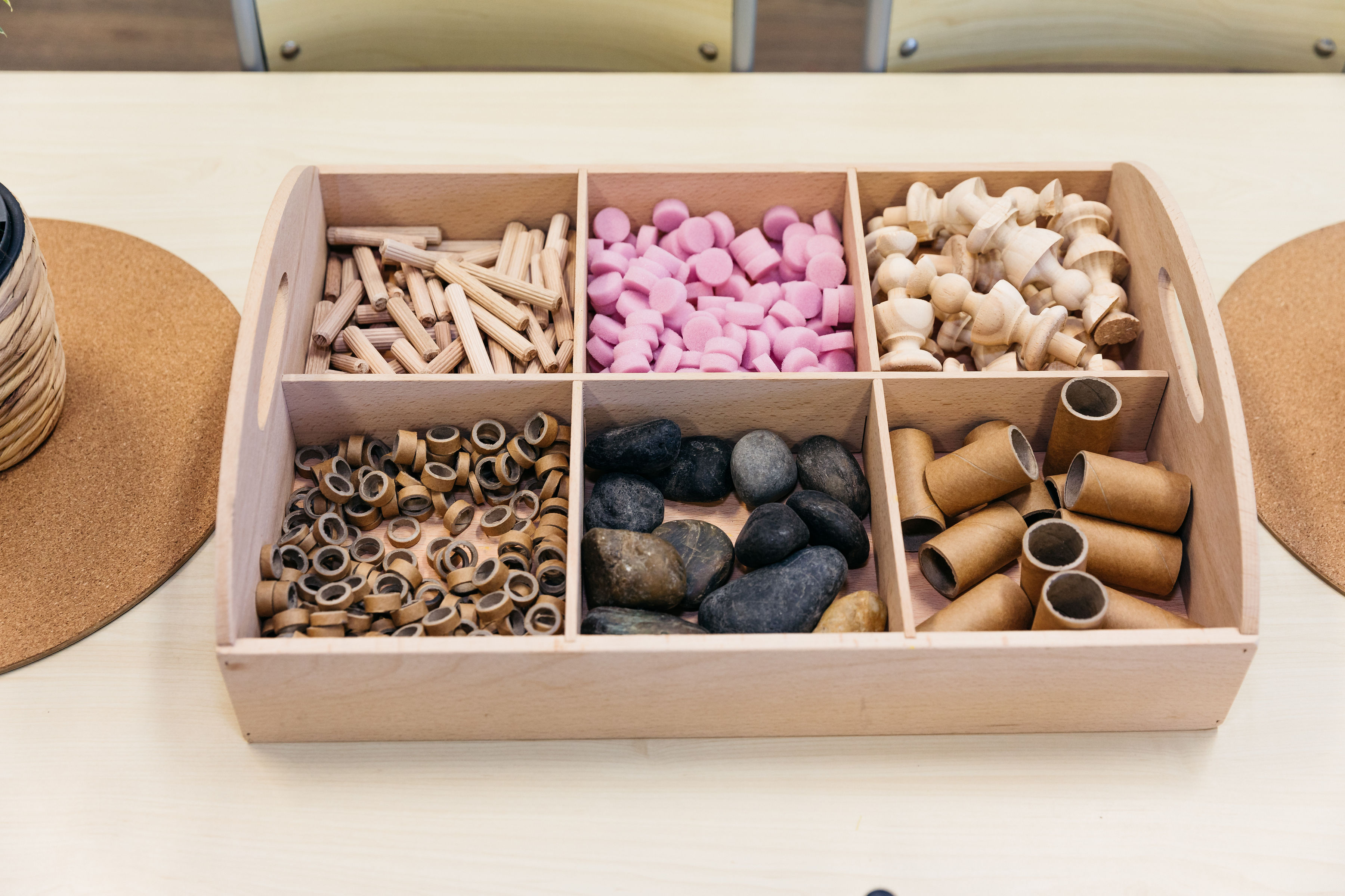 Small loose part resources organised into a neat wooden container at home.