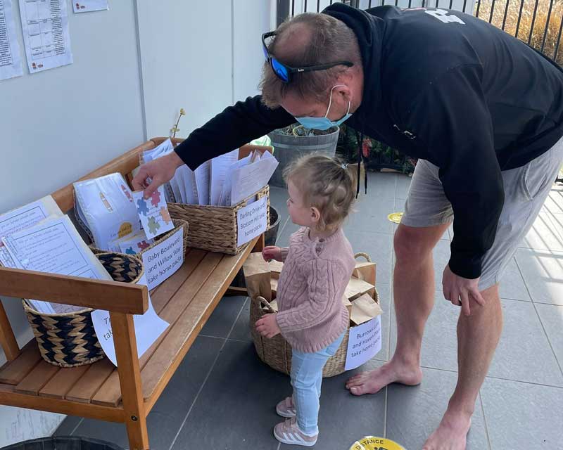 A family stops to collect a Pandemic resource kit for children, an initiative by services to partner with parents and families unable to attend.