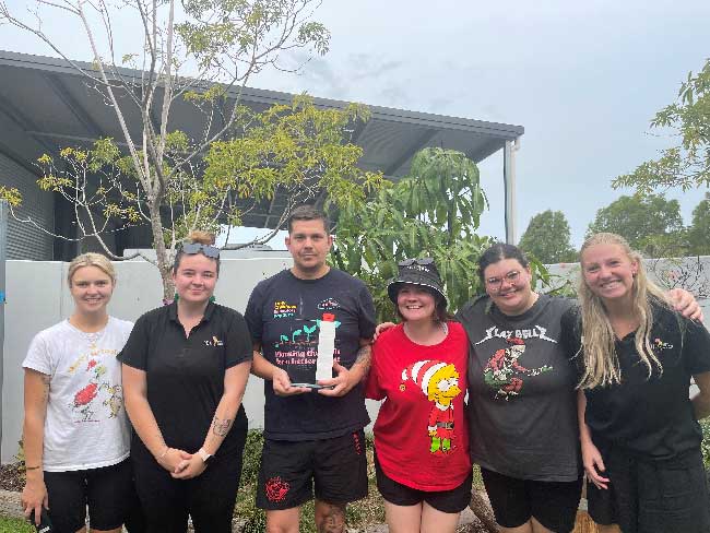 A group of educators from Petit ELJ Coffs Harbour stand together and proudly show off the perpetual award for Centre of the Year.