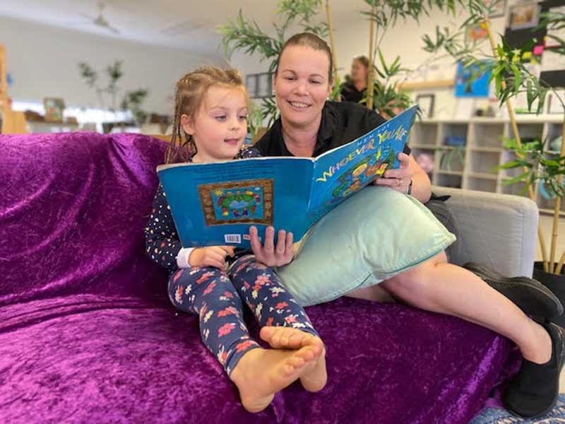 Exceptional Team Member for April 2022 reads a book to a child at Petit ELJ Murwillumbah.