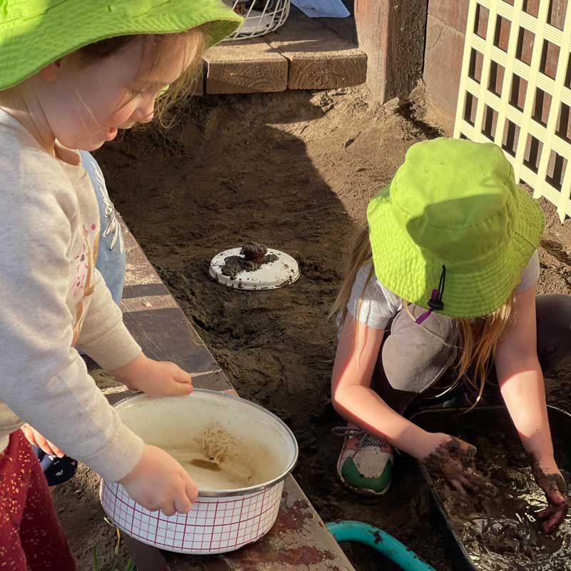 wo children explore a provocation with wet sand and loose-parts focusing on process rather than product