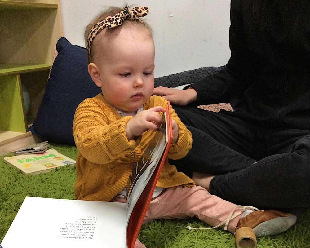 um and baby flipping through book attend baby story time