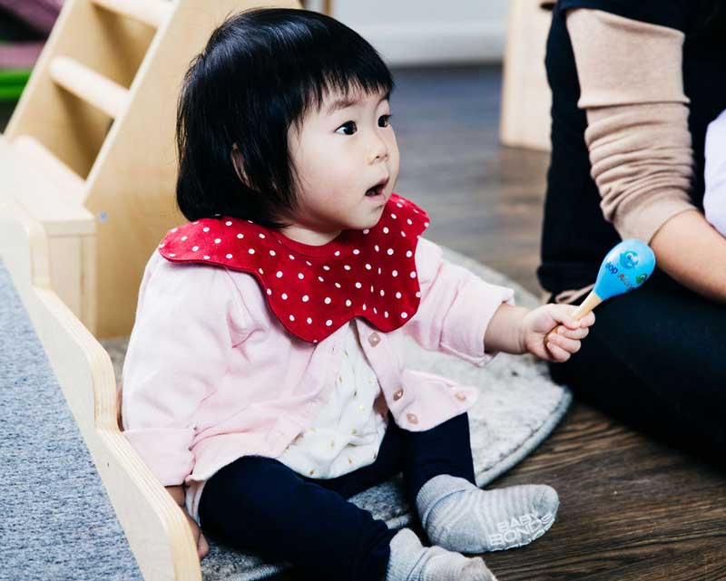 A toddler shakes a maraca. A simple but effective way to introduce movement and music activities for toddlers.