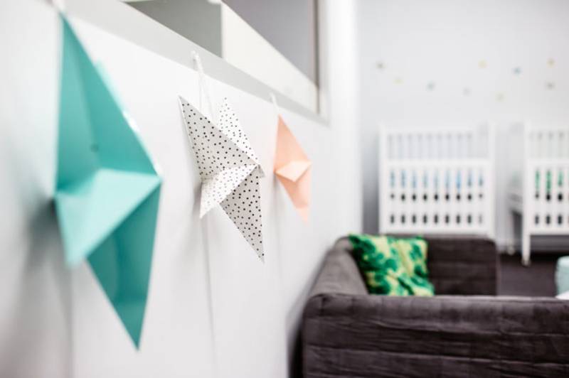 Preparing the nursery for a newborn baby may include decorative stars such as those on the wall of our image, along with the cot and a comfy chair with a pillow.