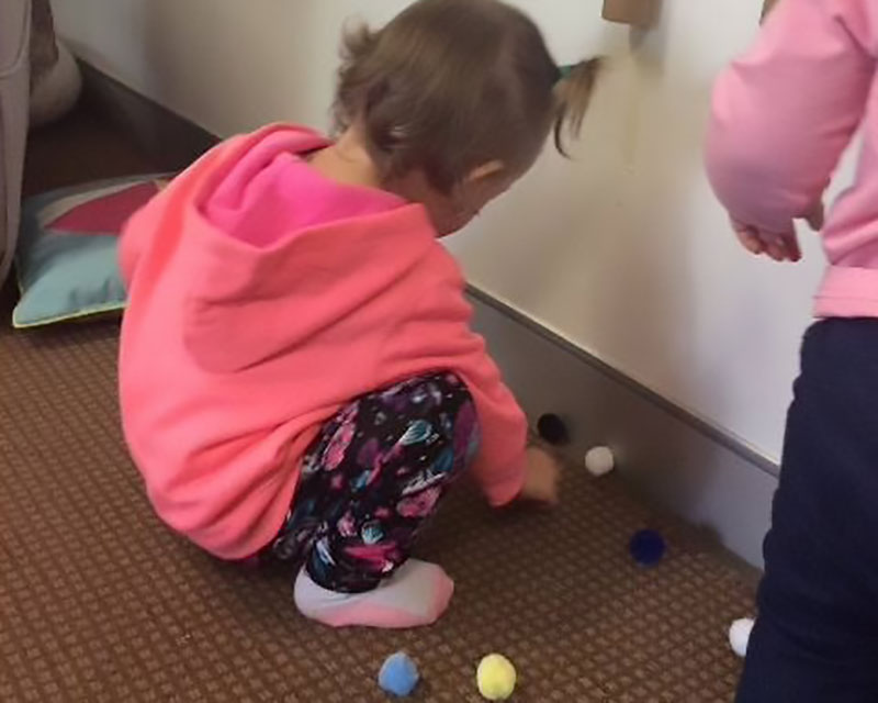 Children play with pompoms, easy-to-make homemade fabric toys for toddlers.