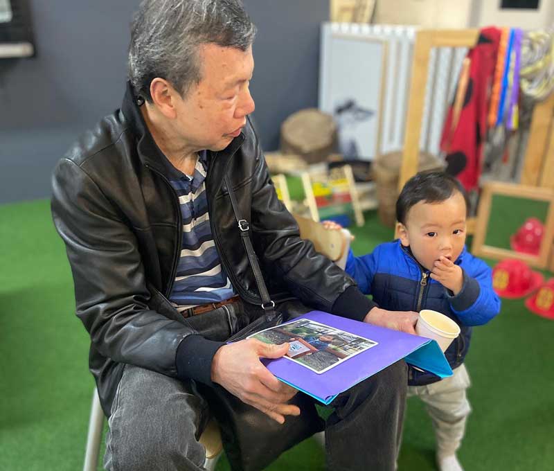 ALT: A man holds a photo of a child holding a sign set in a handcrafted purple and blue frame, while the boy holds onto the man and they share a bite to each thanks to the Australian Father's Day movement.
