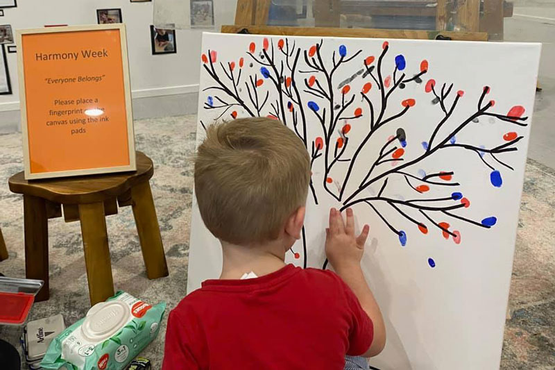 Child adds finger-print paint to their ECEC's Harmony week culturally diverse festival xperience