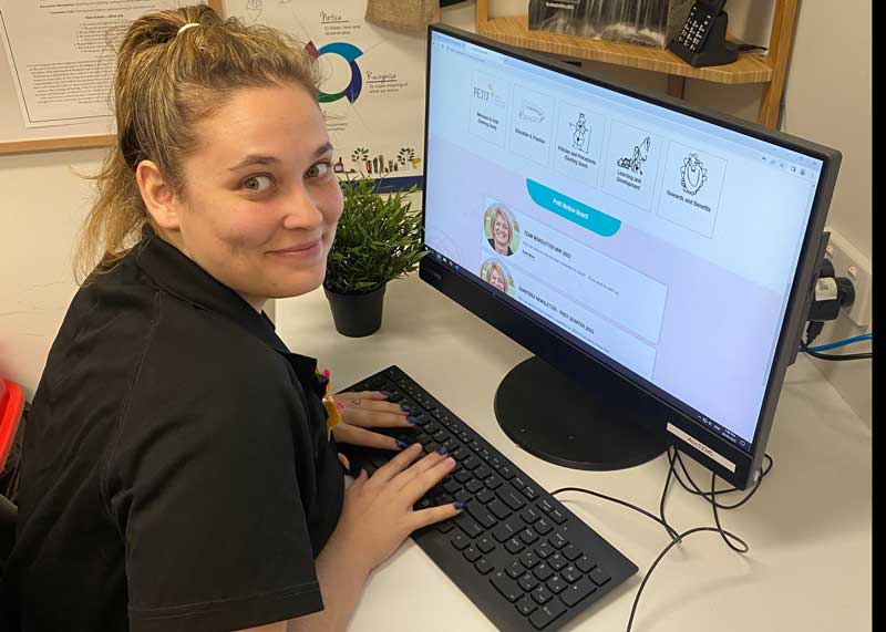 An employee sits at a desk in our office to accesses our education and care learning management system.