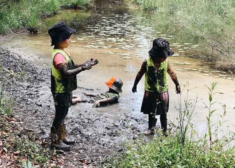 Children from Petit ELJ get soaked in muddy water enjoying the fun of nature play spaces.