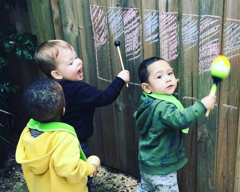 Children play spontaneously with instruments in the outdoor environment - part of the importance of music and movement in early childhood development.