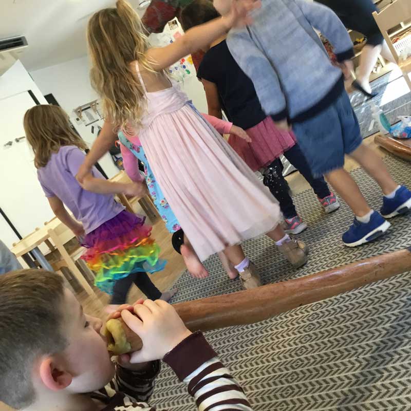 A child plays the didgeridoo while other children dance and experience Australia's Indigenous culture.