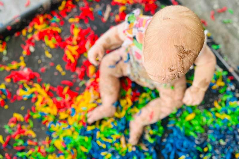 Child sits in an immersive and colourful sensory experience wearing cloth nappies in Australia.