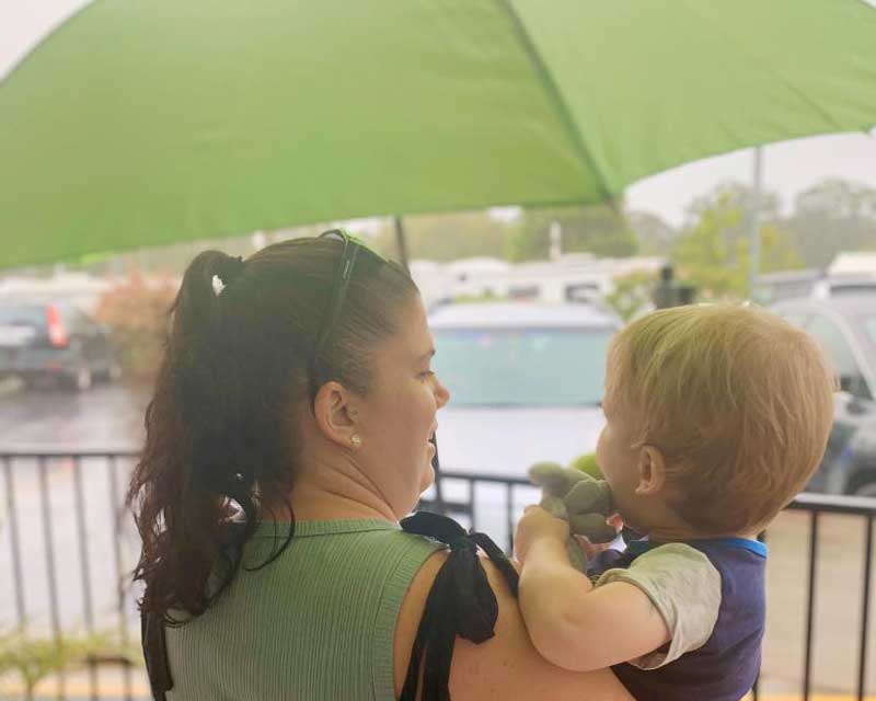 Mother holding baby with umbrella leaving a mothers' group.