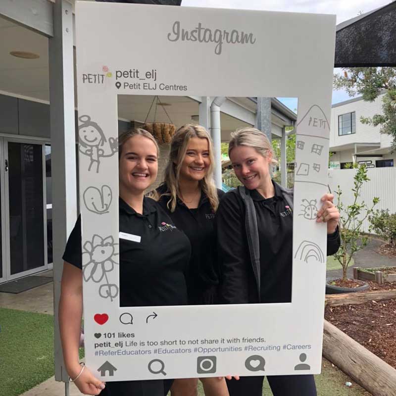 Three Educators hold sign about working in early childhood education and care with friends..