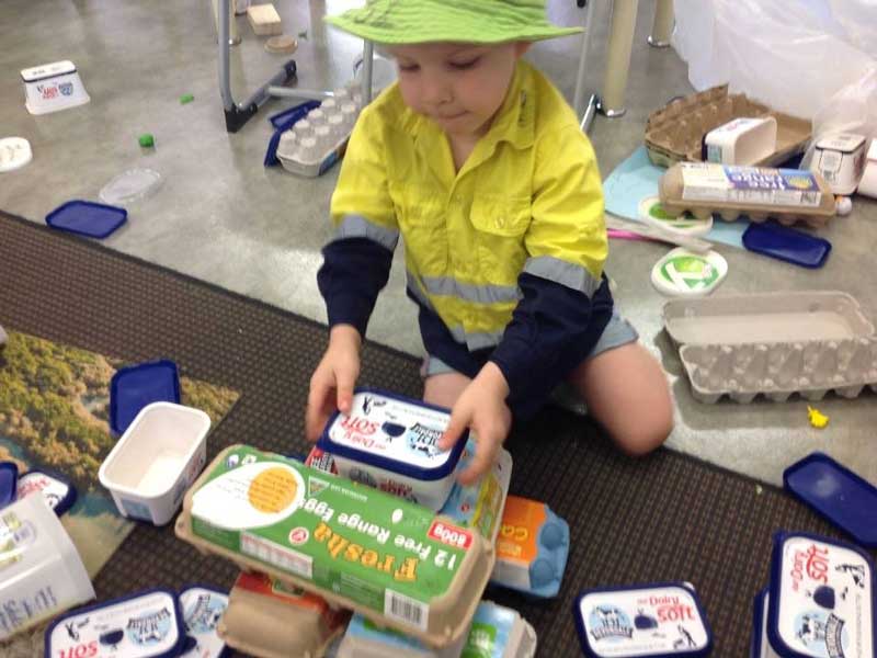 Child playing with reusable containers as blocks - easy DIY toys for toddlers.