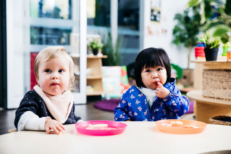 Two children sit side by side at mealtime as Educators observe and look for cues to reassure confident children - another Circle of Security examples in action.