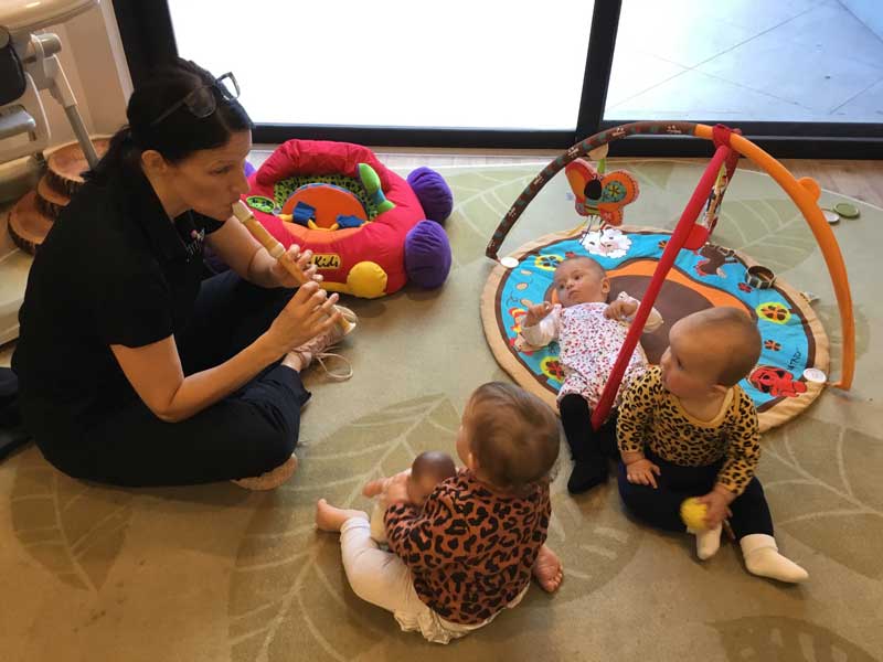 An Educator plays the recorder to babies as part of movement and music activities for children.