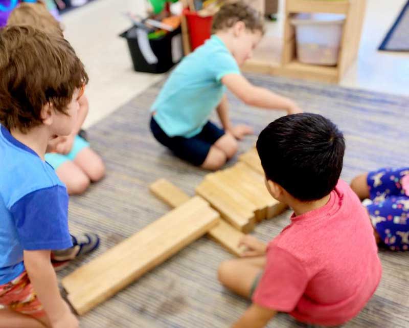 Children play with simple DIY wooden toys and blocks.