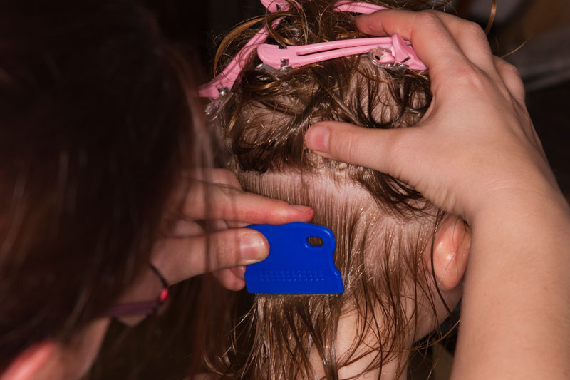 A Parent uses the wet-hair method with a comb to mechanically remove lice and eggs from the hair.