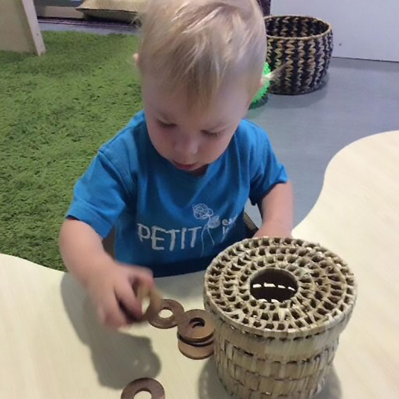 Child pushes metal o-rings through a round slot on a basket. A great idea for a cost friendly handmade toy.