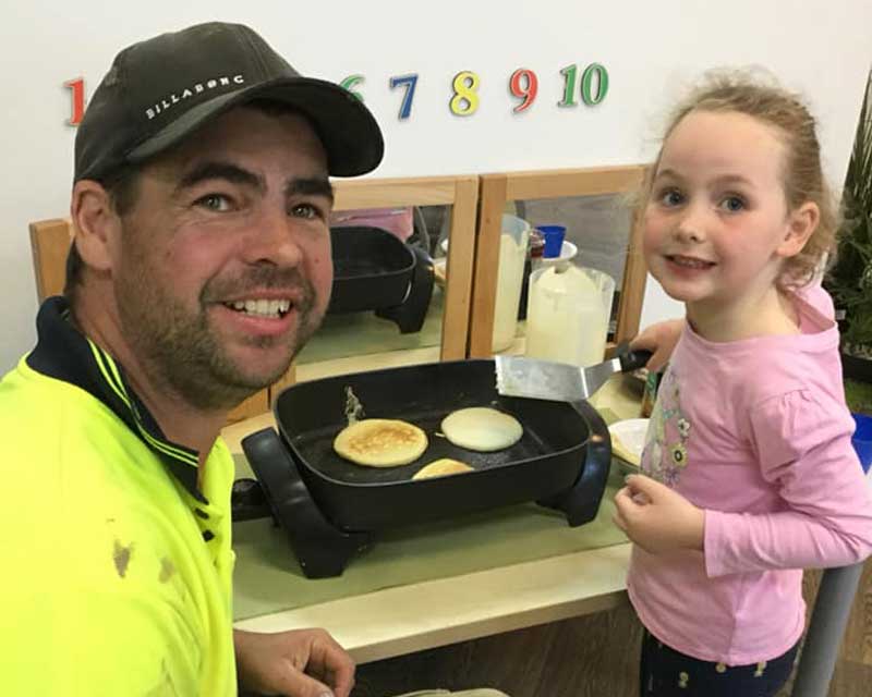 Daughter shows Dad how to make pancakes. Cooking lessons are cool Father's Day activities for preschoolers