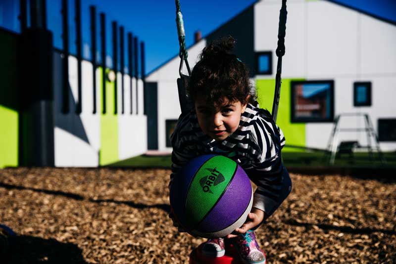 Encouraging children to share: A child plays with a ball on a swing.