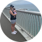 Family member holds a young baby while standing on a bridge and looking out to sea. 