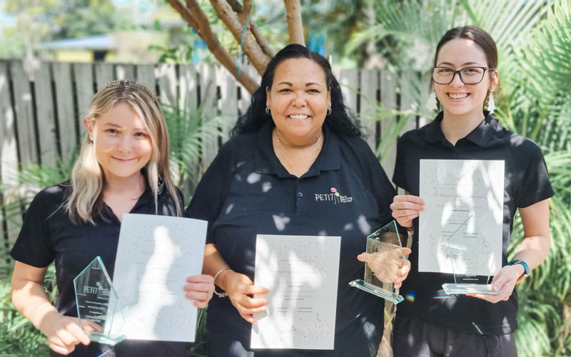 Three educators stand in the shad of a tree holding trophies and certificates. They are our Award of Excellence Winners at Petit ELJ Burdell 2 for 2022.