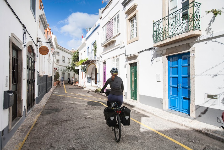 The Best Cycling Routes in Portugal, from the Coast to the Mountains - Lone female bike tourer cycles through an empty street in the Algarve, southern Portugal