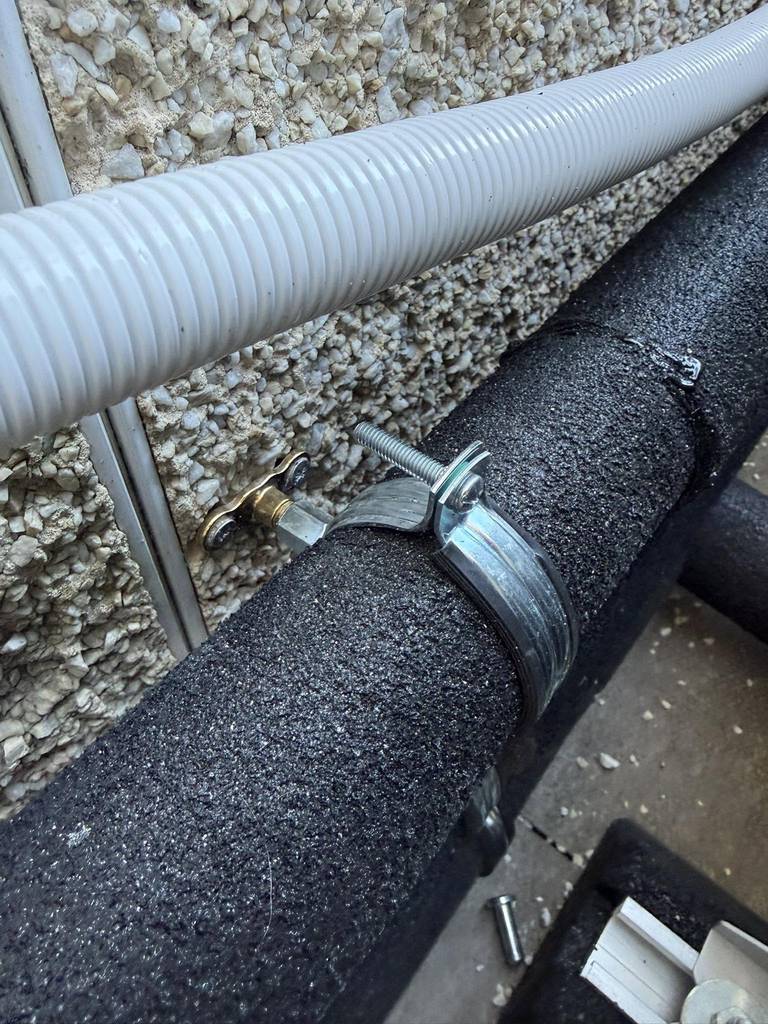 Close-up of insulated external pipework and heavy-duty bracketry
