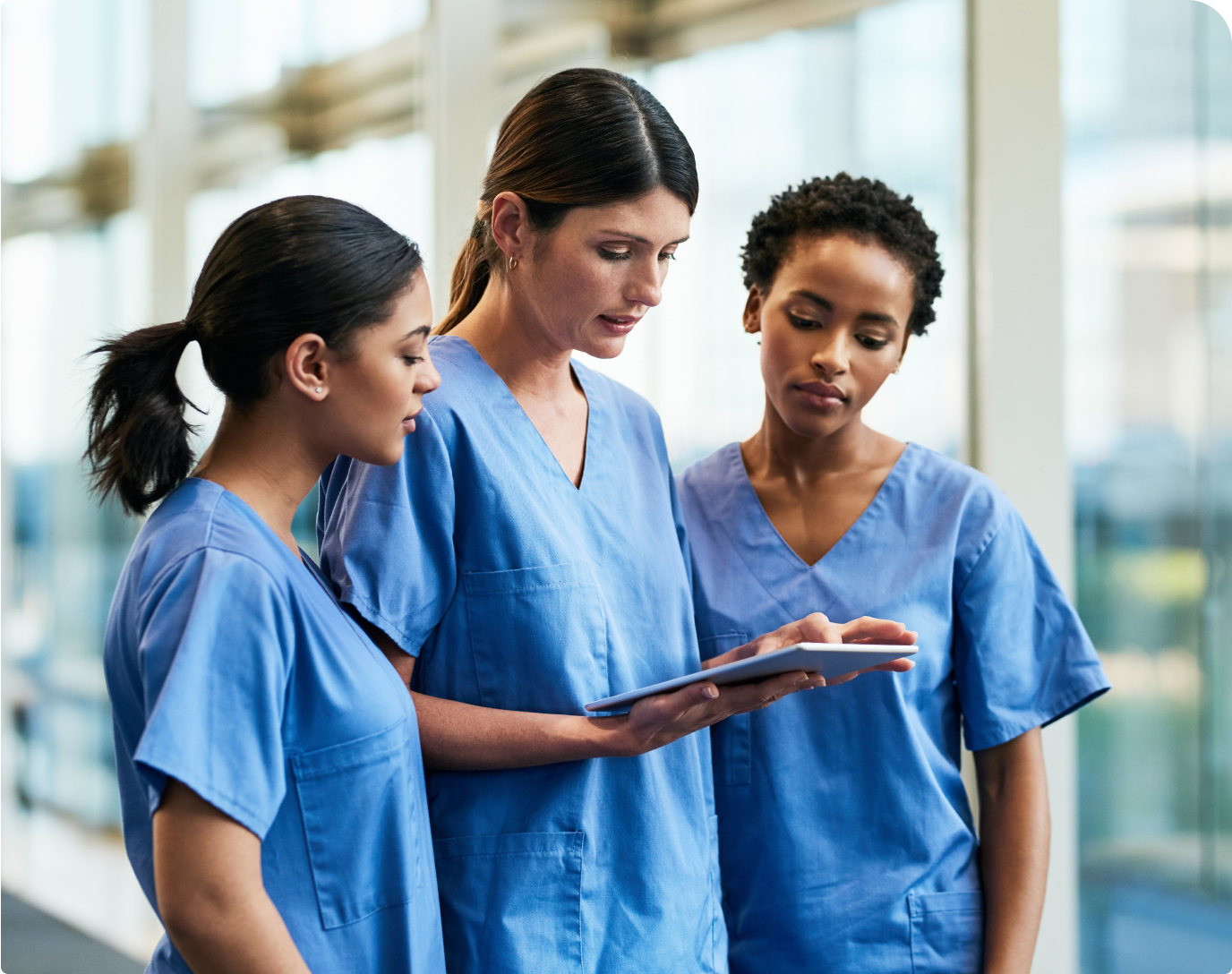 Three nurses reviewing information on a tablet