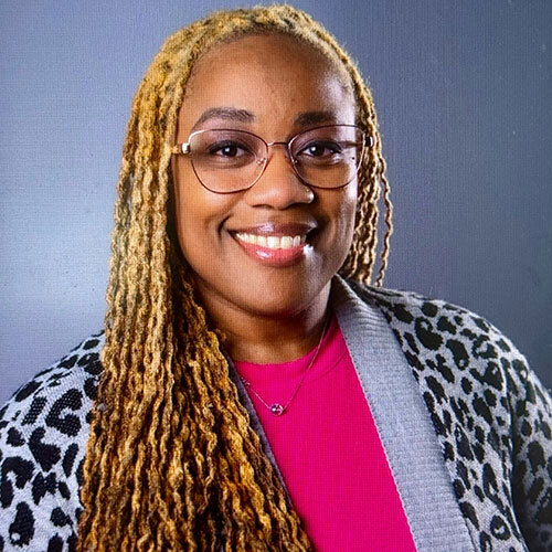 Headshot of woman wearing glasses with a pink shirt and leopard print sweater