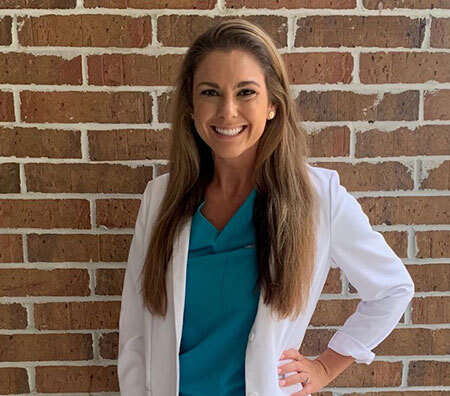 Headshot of Sarah Lilliott wearing blue scrubs and a white labcoat.