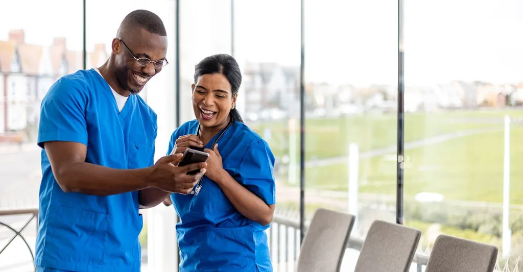 Nurses laughing at a meme on a phone