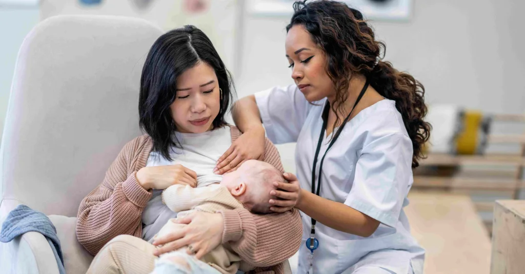 Nurse helping new mother breast feed