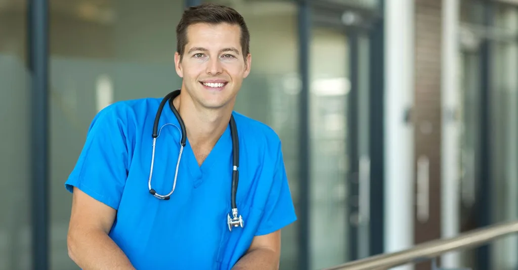 Male nurse wearing scrubs and smiling