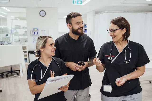 Two female nurses and one male nurse discussing teamwork in nursing
