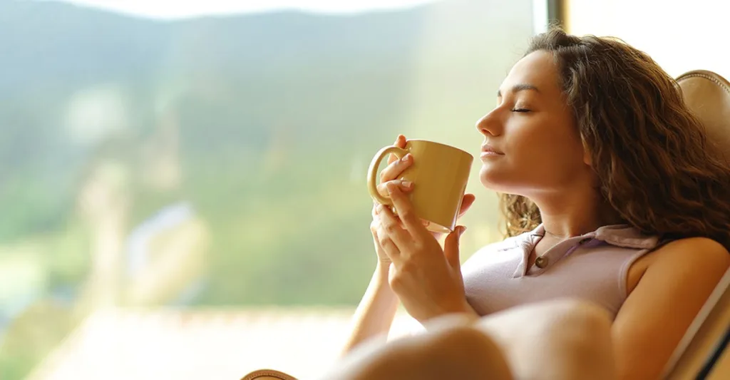 Woman hired by best travel nurse companies relaxes, drinks coffee before shift