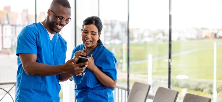 Nurses laughing at a meme on a phone