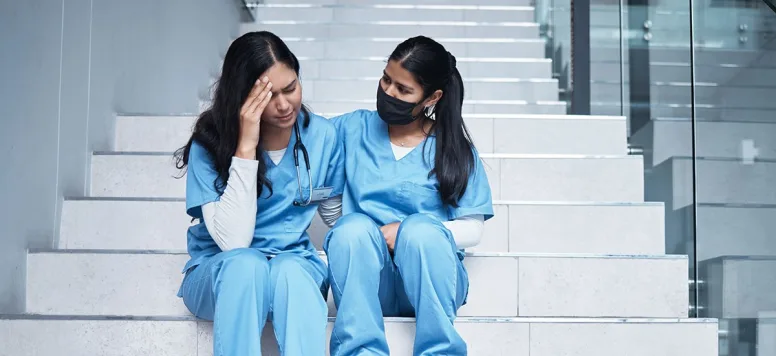 Nurse comforting colleague with nurse burnout symptoms