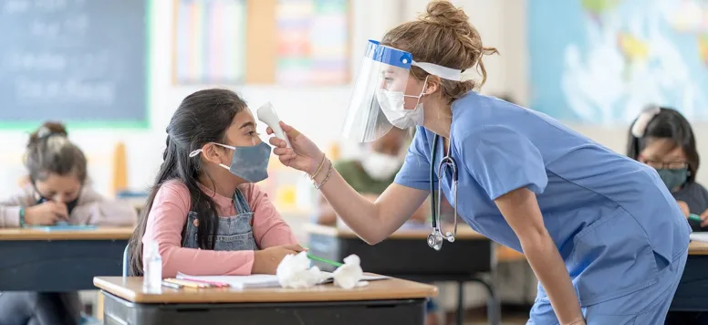 School nurse taking temperature of student