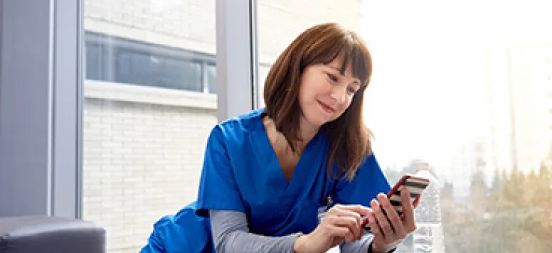 A nurse smiling at her phone as she uses social media at work