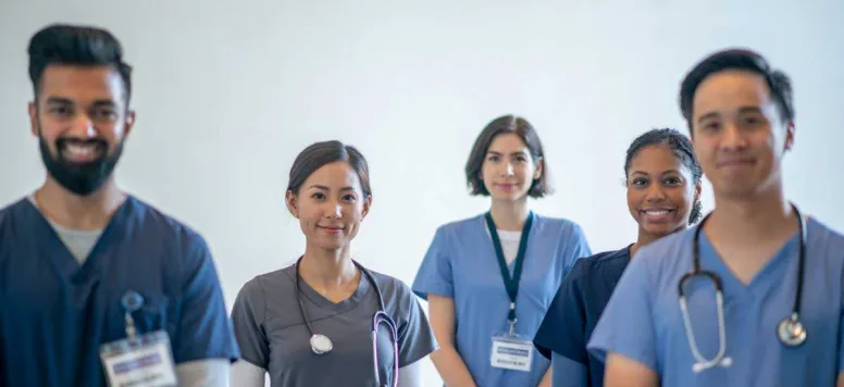 Five nurses standing in a group looking at the camera and smiling