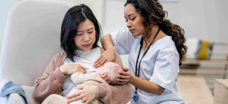 Nurse helping new mother breast feed